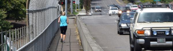 一个女人安全地在繁忙街旁人行道上慢跑